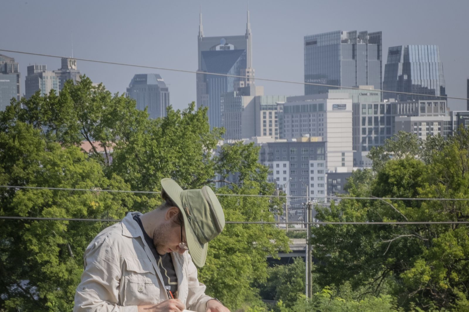 A VISR researcher recording field notes at a survey site, with the downtown Nashville skyline in the background